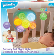 Kidoozie Sensory Ball Night Light toy set in its retail packaging, featuring a baby interacting with a colorful sensory ball toy inside a crib. The box highlights 6 different sound effects, age suitability of 6+ months, and includes a small inset photo of a baby playing with the toy.