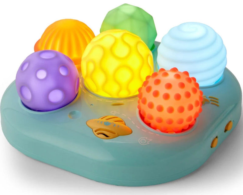 A colorful baby sensory toy with a mint green base and six textured, glowing balls in purple, yellow, green, orange, and light blue, set against a plain white background.
