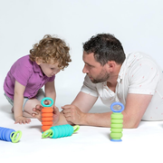 Man and child playing with colorful Krumples Plungy toy from Smart Games on a white background.