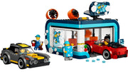 A LEGO building set showing a blue and teal ice wash station with a red car inside, a gray and yellow car outside, and two minifigures on a plain white background.