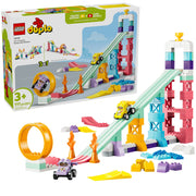 LEGO Duplo 12042 Niki Racing Car Builder set shown with its retail box and assembled toy components on a white background. The set includes a tall pink and blue tower, a mint green ramp, an orange loop, small cars, and assorted building blocks.