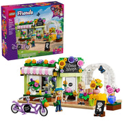 LEGO Friends Flower Shop building set shown with the retail box and assembled model on a white background. The set includes a flower shop storefront with colorful flowers, an arched entrance, a purple heart-shaped bicycle, and two minifigures.