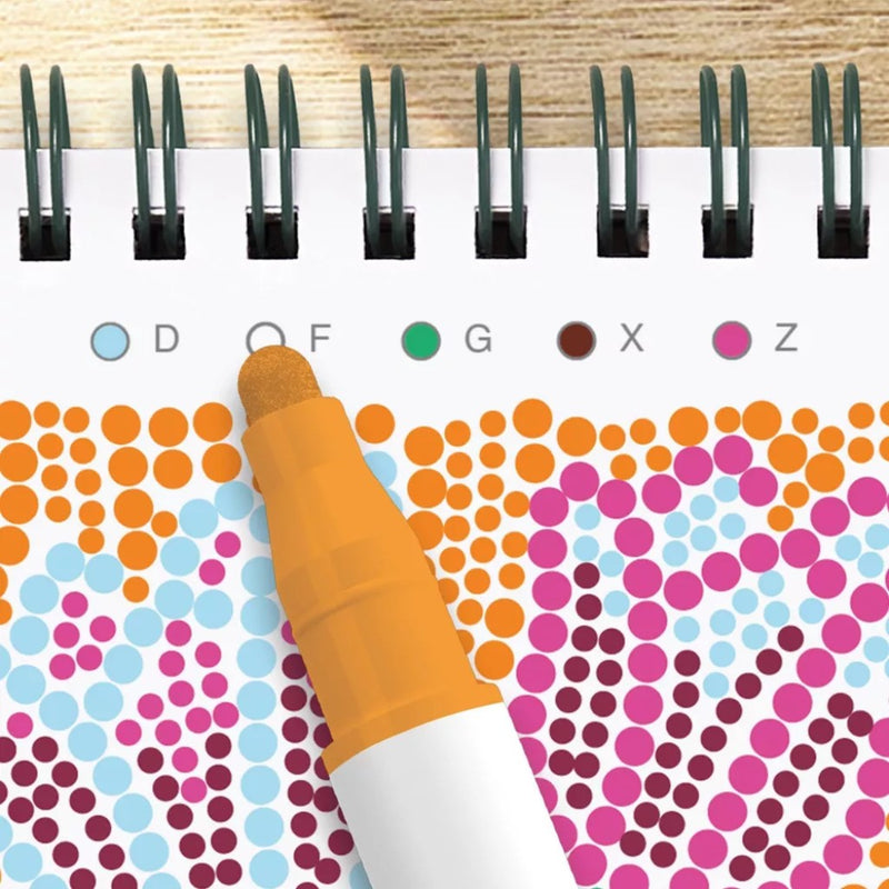 Coloring page with polka dot patterns and a pen pointing to 'D' on a wooden surface.