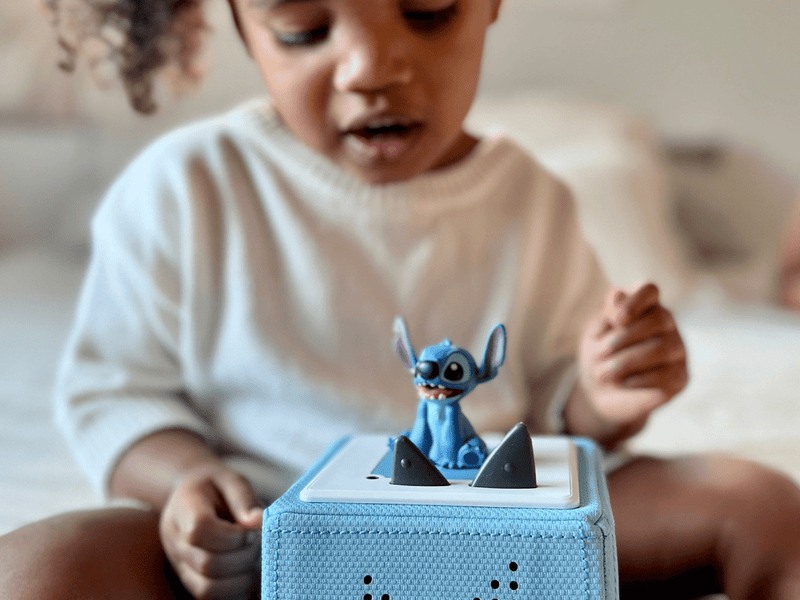 Child playing with blue Stitch Tonie figure on Toniebox audio system