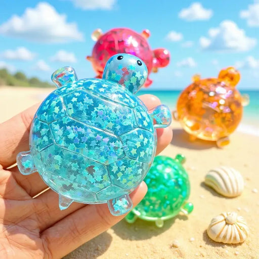 Blue glitter sea turtle squishy toy held on beach with colorful turtles behind it.