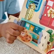Child's hand interacting with Hape's Lock & Learn Playboard on a carpeted floor.