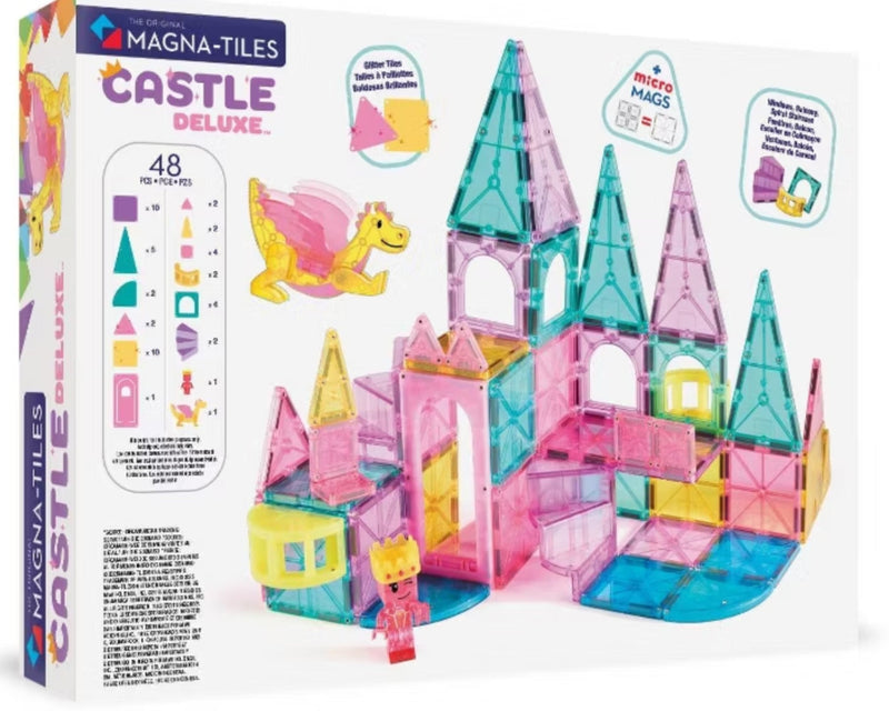Magna-Tiles Castle Deluxe toy set in its retail packaging, featuring a white box with colorful illustrations of a pink and blue castle, a yellow dragon, and various magnetic tile pieces.