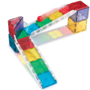 A magnetic tile construction set with translucent colorful square and triangular blocks forming a ramp and bridge structure, with a small red ball on top, photographed on a white background.