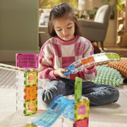 Child playing with colorful building blocks on a carpeted floor.