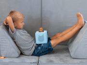 Child relaxing on couch with Tonie box speaker and Cars character figure