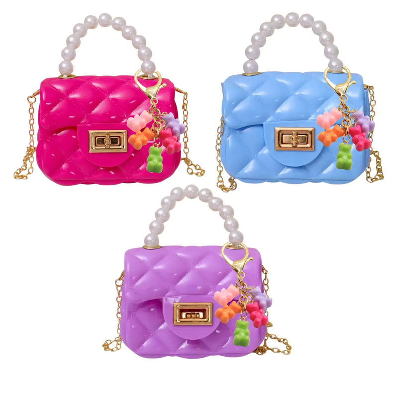 Three quilted handbag charms in pink, blue, and purple, each with a pearl handle, gold-tone clasp, and colorful grape charm, shown on a white background.