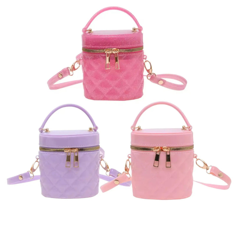 Three quilted cylindrical handbag charms in pink, purple, and light pink, each with a top handle, zippered front, and detachable shoulder strap, shown on a plain white background.