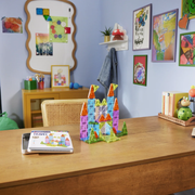 Colorful magnetic building blocks on a wooden table with a child's room in the background.