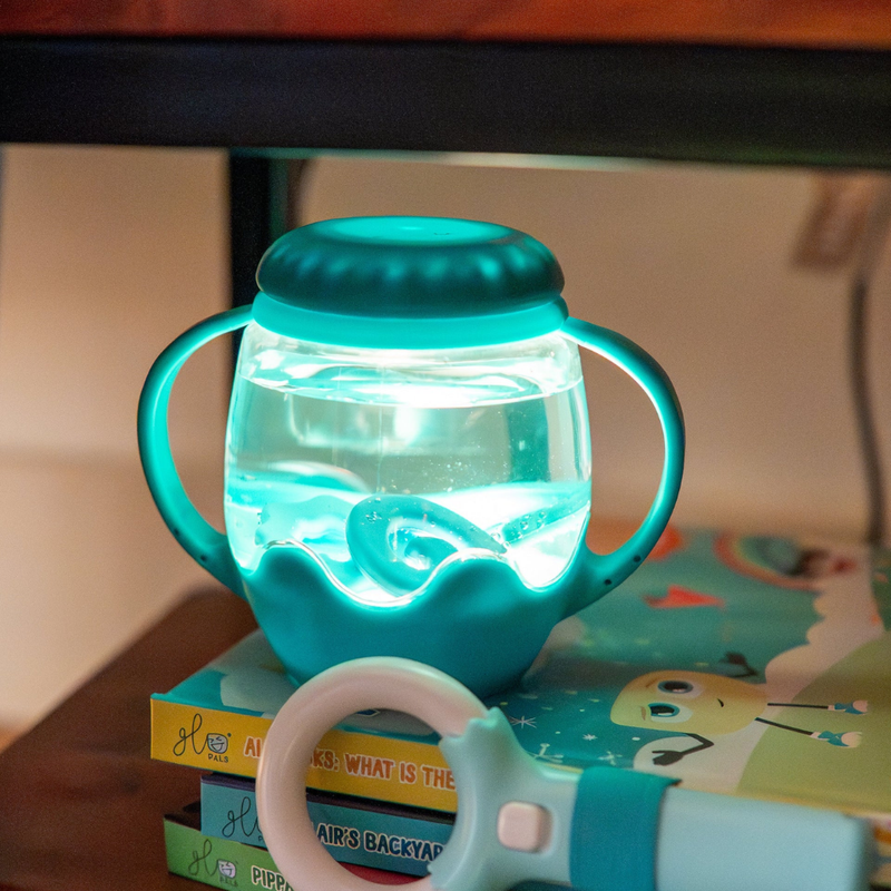 Lighted Mini Sensory Jar from Glo pals.  Filled with water and light resting on a stack of kids books.