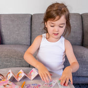 Young girl playing with Mini Transfer Magic Flower Fairies on couch with colorful accordion book