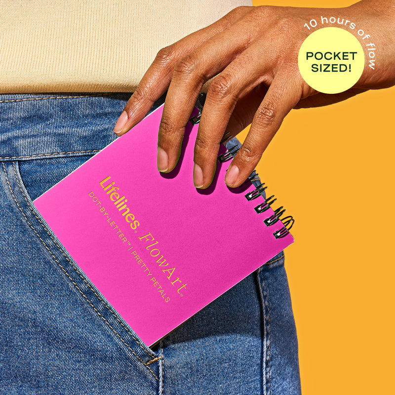 Pink pocket-sized FlowArt Mini notebook being pulled from jeans pocket by hand