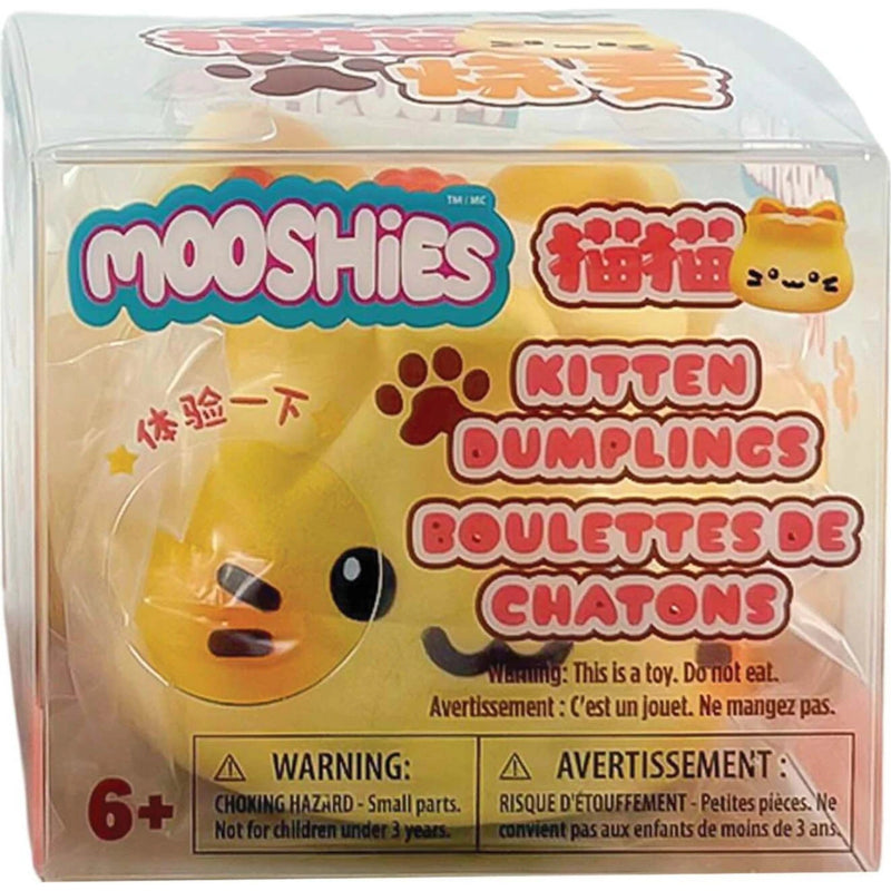 MOOSHIES Kitten Dumplings toy in its original clear plastic packaging, featuring a yellow plush dumpling character with black eyes and a black whisker, surrounded by colorful product text and warning labels.