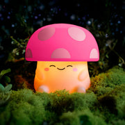 Cute mushroom-shaped night light with a pink cap and off white body on a grassy background.