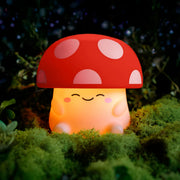 Cute mushroom-shaped night light with a pink cap and off white body on a grassy background.