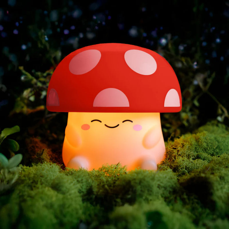 Cute mushroom-shaped night light with a pink cap and off white body on a grassy background.