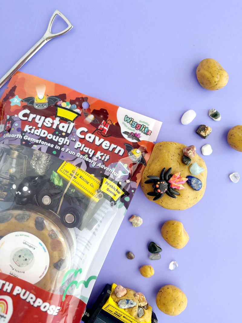 Crystal Cavern KidDough Play Kit with yellow dough balls, gemstones, and excavation tools on purple background