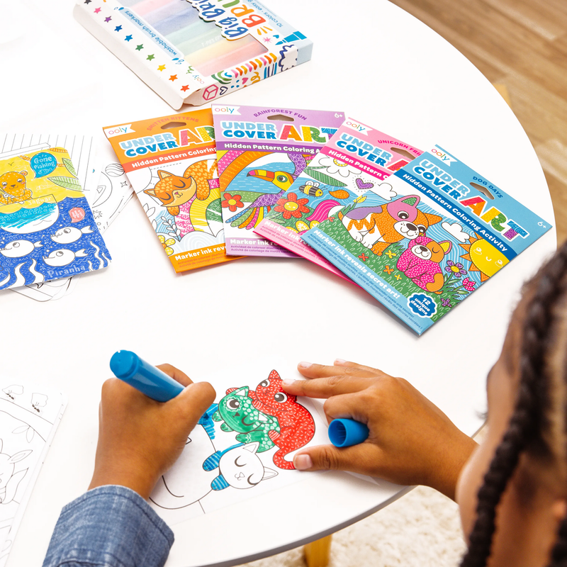 Child coloring OOLY hidden pattern coloring books with markers on white table