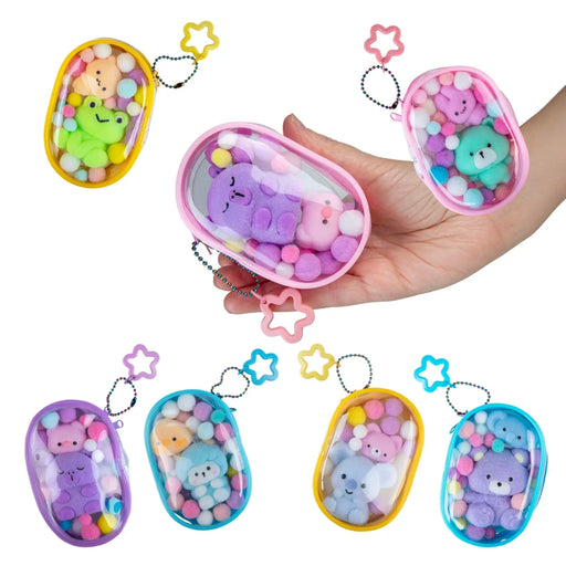 A hand holds a pink oval charm case filled with pastel pom-poms and a plush bear, with five additional color variants arranged around it on a white background.
