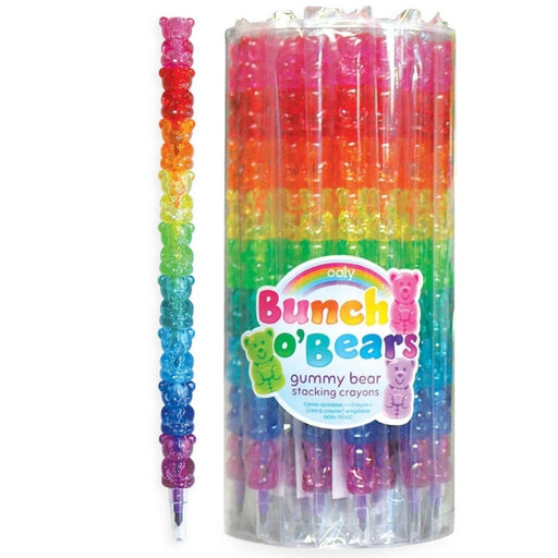 A pack of rainbow-colored gummy bear stacking crayons in a clear plastic cylinder, with one crayon shown standing outside the tube. The crayons are stacked in horizontal rainbow bands of pink, orange, yellow, green, blue, and purple, with each section featuring a translucent gummy bear detail.
