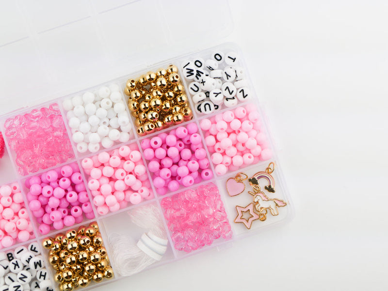 Pink bead bracelet kit with letter beads, gold beads, charms, and elastic cord