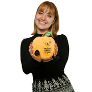 Woman holding orange pumpkin plushie with 'Trick or Treat Yo'self' text and winking face