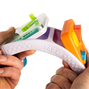 Colorful toy set with PlayTab branding allowing interchangeable toddler toys to be inserted in the case. Held by a person on a white background.