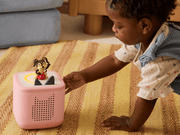 Child playing with pink TonieBox starter set featuring Playtime Puppy character on colorful rug