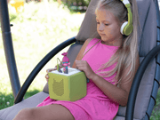 Young girl using Tonie Trolls Poppy figure with green Toniebox and headphones outdoors
