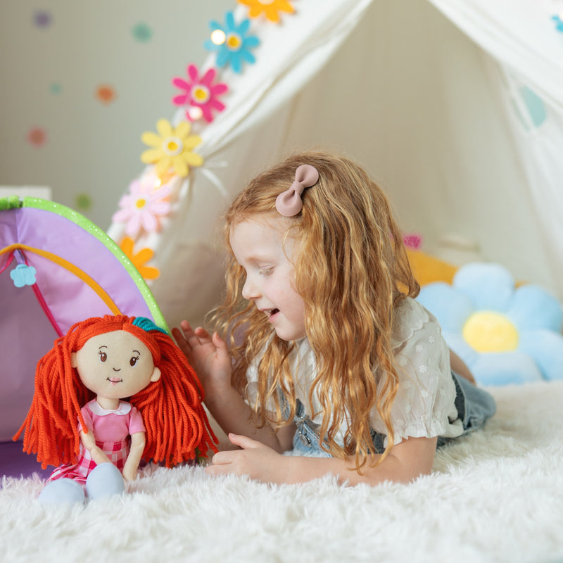 Young girl playing with Groovy Girls Poppy red-haired plush doll in decorated playroom tent.