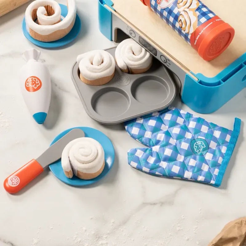 Play kitchen set with cinnamon rolls baking accessories on a marble surface.