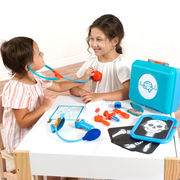 Two children playing with a toy doctor set on a white table.