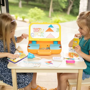 Two children playing with 'school' at a table indoors.