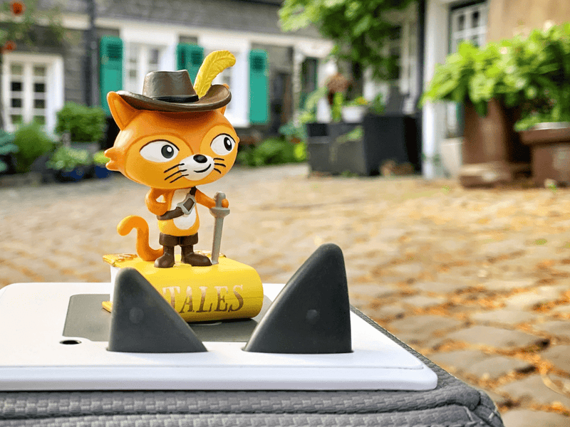 Orange Puss in Boots Tonie figurine with hat and feather on laptop with shark fins