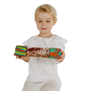Child holding a rainbow calm down bottle on a white background.