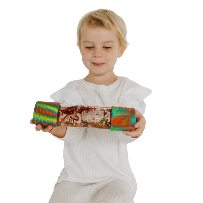Child holding a rainbow calm down bottle on a white background.