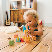 Child playing with castle themed building blocks on a wooden floor.