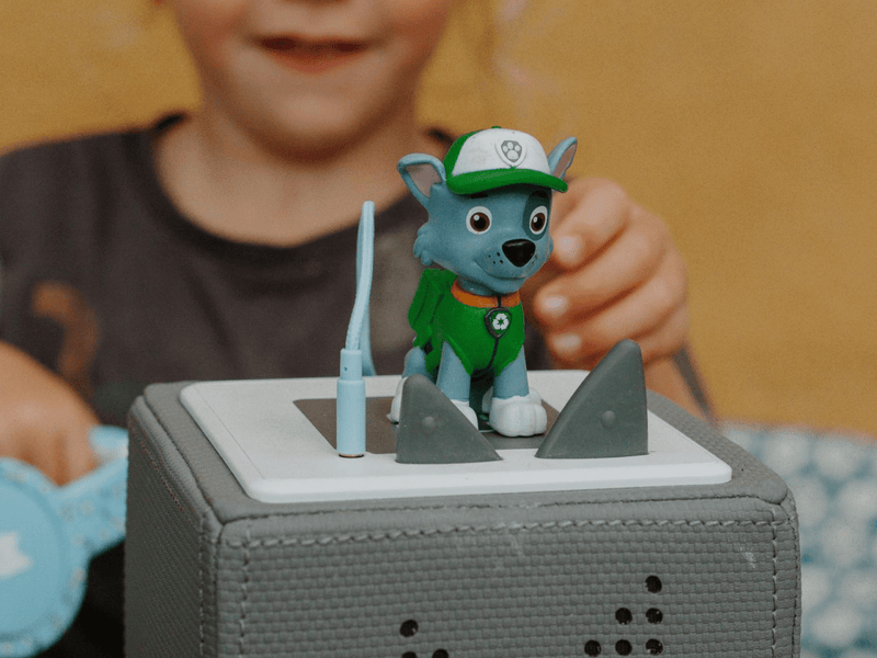 Paw Patrol Rocky Tonie figure on grey Toniebox with child playing in background