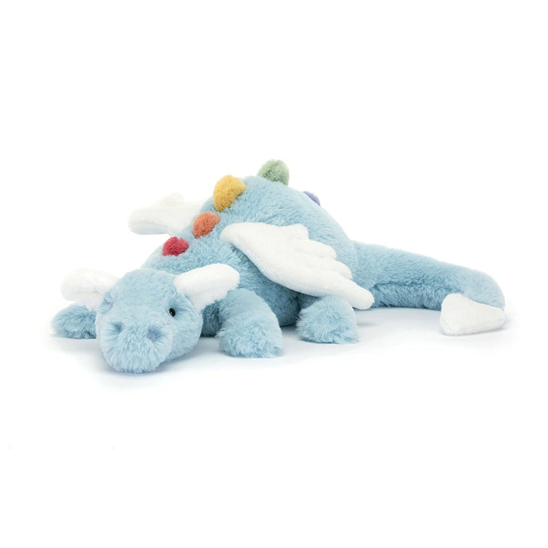 Sky blue plush dragon toy with white wings and colorful pom-poms lying on white background