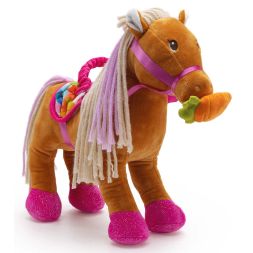 A plush toy horse in brown with a cream and lavender faux-fur mane, a pink halter, a colorful saddle, and glittery pink hooves, holding an orange carrot on a white background.