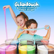 Two children smiling and stretching colorful geladough in a playful studio scene. Several clear jars filled with pastel dough are visible in the foreground, and the words 'Geladough gourmet scented fidget dough' appear at the top against a blue gradient background.