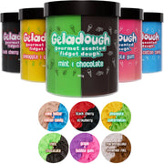 Six tubs of Geladough gourmet scented fidget dough are arranged in a row on a white background, with six circular flavor swatches below. The center tub is mint & chocolate, which is green and dark brown/black, while the surrounding tubs show other flavors in different colors including yellow, pink, blue, and black.
