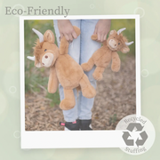 Person holding two brown Highland cow plush toys with horns outdoors