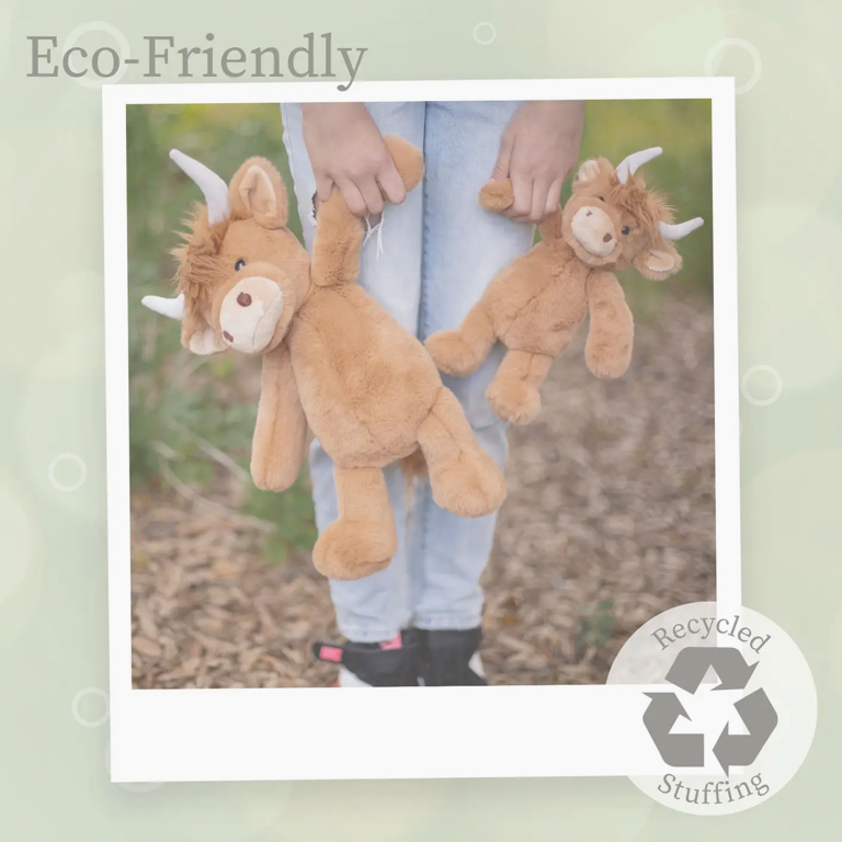 Person holding two brown Highland cow plush toys with horns outdoors