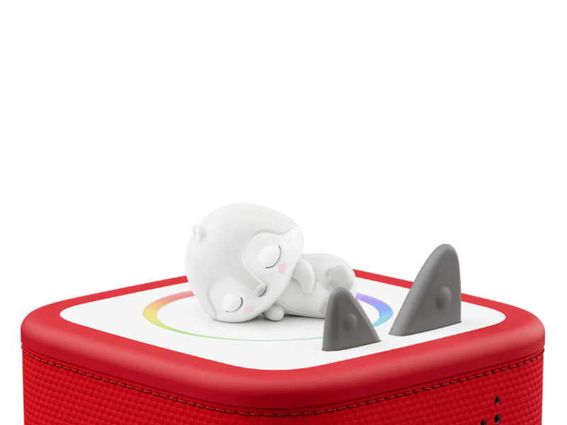 White penguin Tonie figure lying on red Toniebox with gray spikes visible