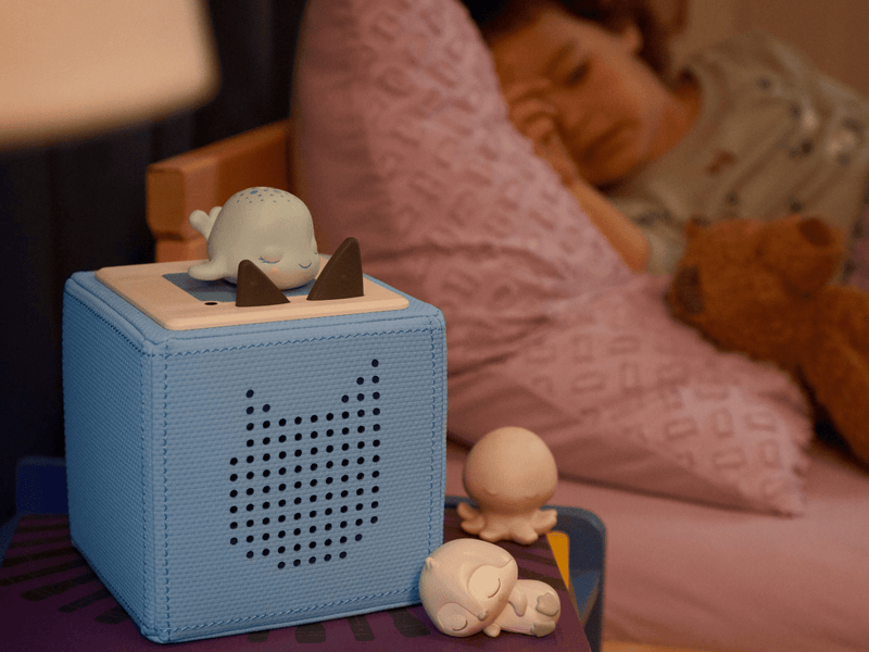 White penguin Tonie figure on blue audio cube in bedroom setting